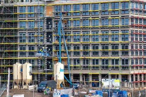 Large construction site, scaffolded shell of an office building complex, air hoses for construction