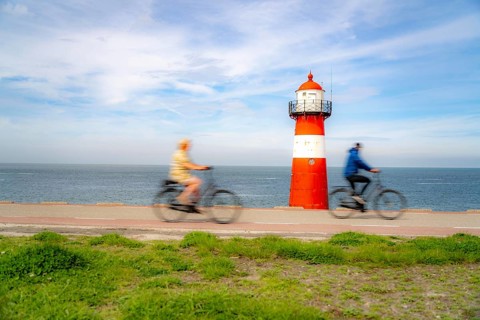 North Sea dyke near Westkapelle, Westkapelle Laag lighthouse, cyclists on the Zeeuwse Wind Route