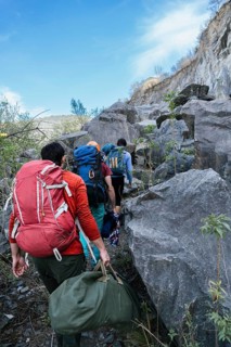 Rear view of a group of hikers hiking picturesque mountain trails in a row, immersed in the beauty
