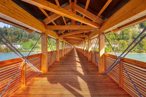Interior view of a wooden bridge with impressive play of light and shadow and view of the river,