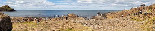Panorama of people on basalt columns with sea view under cloudy sky, Giant Causeway