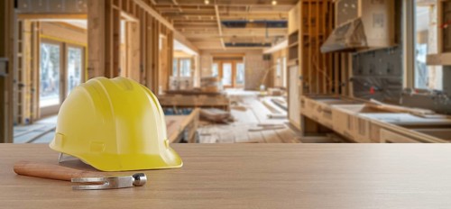 Yellow hard hat and hammer on a wood background with home renovation in construction site in the