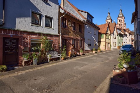 Residential houses with floral decorations, bench and the twin towers of Amorbach Abbey Church in