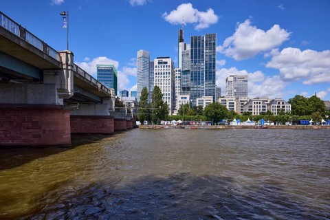 Skyscrapers and Untermainbrücke with Main river under blue sky with cumulus clouds in Frankfurt am