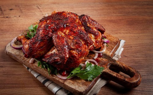 Whole fried chicken, with spices, grilled chicken, on a chopping board, top view, homemade, no