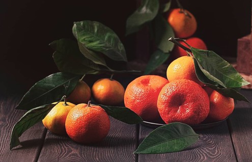 Fresh tangerines with leaves, close-up, rustic, on a wooden table, horizontal, no people