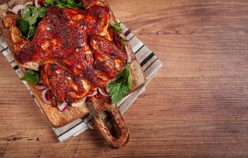 Whole fried chicken, with spices, grilled chicken, on a chopping board, top view, homemade, no