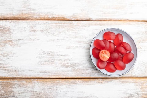 Jelly tomato candies on white wooden background. copy space, top view, flat lay