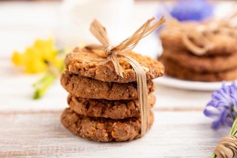 Oatmeal cookies with spring snowdrop flowers bluebells, narcissus and cup of coffee on white wooden
