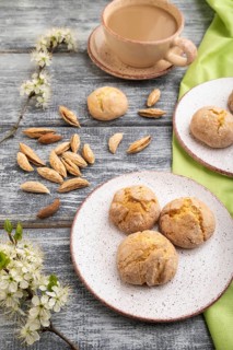 Almond cookies and a cup of coffee on a gray wooden background and green linen textile. Side view,