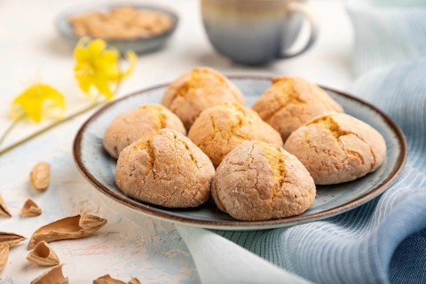 Almond cookies and a cup of coffee on a white concrete background and blue linen textile. Side