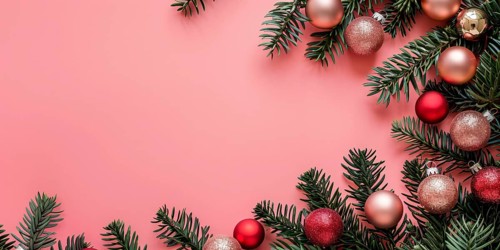Christmas flatlay with red and pink colored tree baubles with white fir branches on pastel