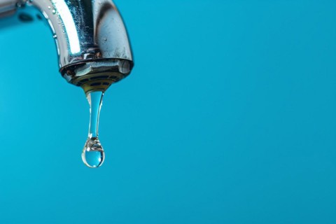 Single drop of water coming out of water tap on blue background. KI generiert, generiert, AI