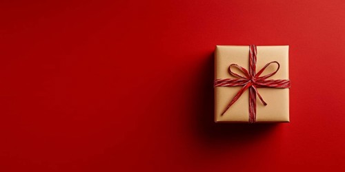 Banner with small Christmas gift box wrapped in kraft paper on red background with copy space.