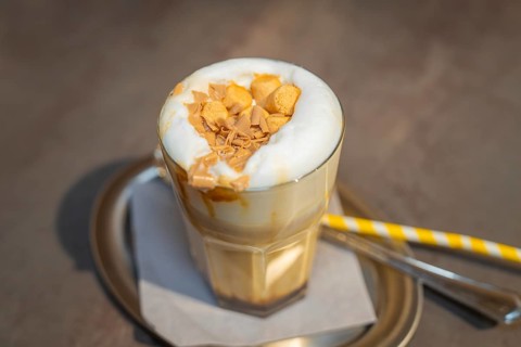 A glass of latte with creamy topping and biscuit crumbs on a serving tray, autumn creations, Cafe