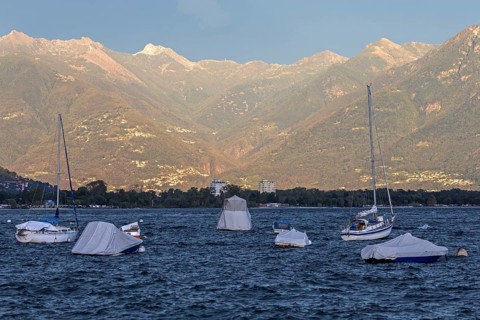 Boats lying in the water, Locarno, Lake Maggiore, surrounding mountains in the evening light,