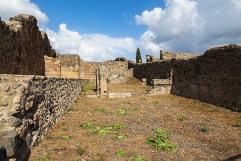 Old stone and terracotta brick wall and building structures in yard covered with brown soil and