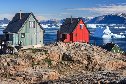 Typical Greenlandic houses in front of icebergs, Inuit settlement, summer, sunny, Uummannaq, West