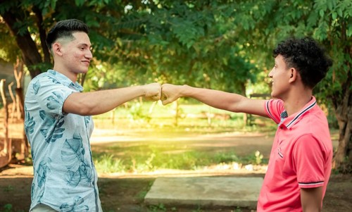 Two young men clashing their fists, image of two young men bumping their fists in a friendly way,