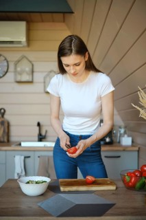 Young woman peels core of tomatoes while cooking a vegetable salad