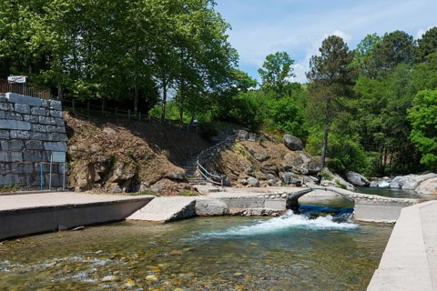 Ein ruhiger Fluss fließt durch ein Gebiet mit einer kleinen Brücke und einer Steintreppe, umgeben
