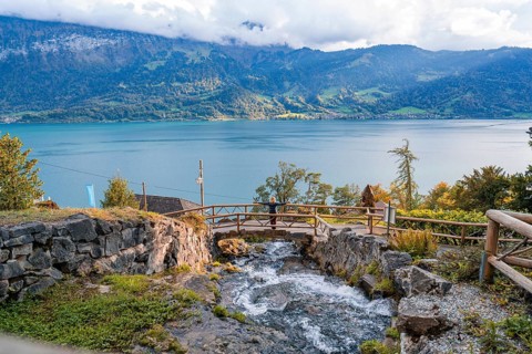 Idyllic stream flows into a lake, surrounded by autumnal mountain landscape, Lake Brienz,