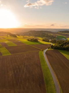 Sprawling fields in the evening light with a winding road under a warm glowing sunset, Gechingen,