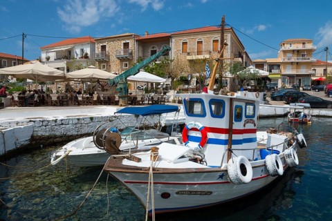 Traditional fishing boats in the harbour in front of a coastal town with historic buildings, Agios
