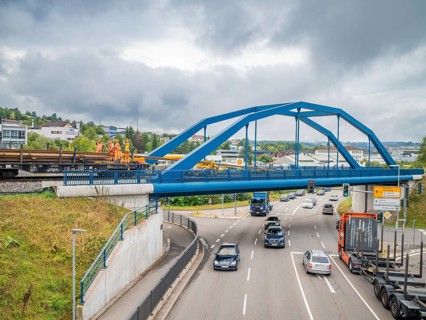 Blue painted bridge with construction workers and passing traffic, track construction, rail