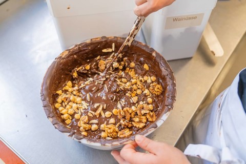 Mixing nuts in a bowl filled with chocolate, Burch Schokolade production, Haselstaller Hof,