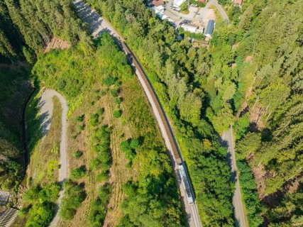 Railway line through dense forest from a bird's eye view, track construction, rail delivery for