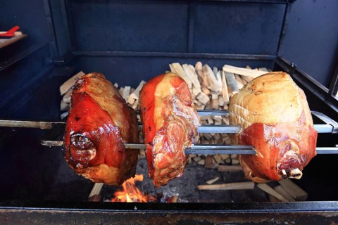 Pork knuckles are grilled on a spit over a wood fire
