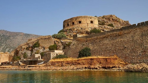Ancient fortress with round tower on the coast, surrounded by water and rocks, Venetian sea