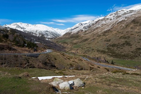 Großes Tal in den Bergen mit verschneiten Gipfeln, einer Straße und bewölktem Himmel, nördlich von