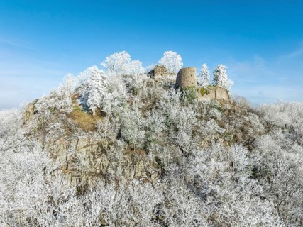 Aerial view of the snow-covered Hegau volcano Mägdeberg, with remains of a castle wall, surrounded