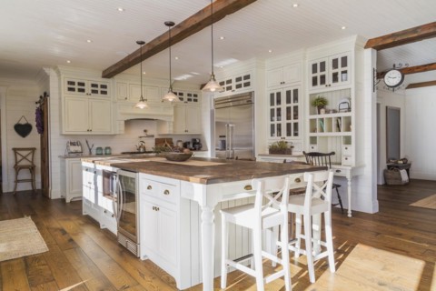 White painted maple wood antique style cabinets with tan coloured quartz countertops, island with