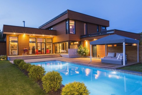 Rear of modern cube style home with stained horizontal wood cladding, in-ground swimming pool and