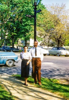 Full-length portrait of an elegantly dressed man and woman standing on the street next to a