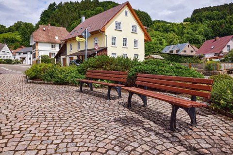 Benches, pavement made of cobblestones, car park, multi-family houses, hilly landscape with