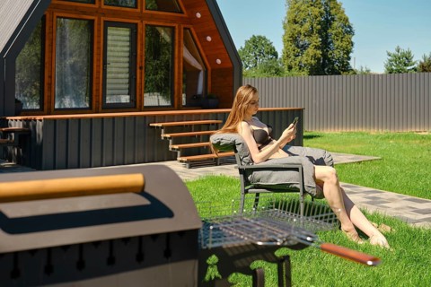 Serene woman enjoying a peaceful moment on a sun lounger in the backyard of a modern A-frame house