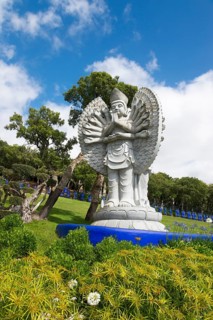 Statues of Buddha in a manicured garden with trees and a blue sky, Bacalhôa, Bacalhoa Buddha Eden,