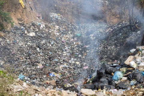 Coking rubbish dump, rubbish pit with waste and plastic rubbish, karst landscape near Vang Vieng,