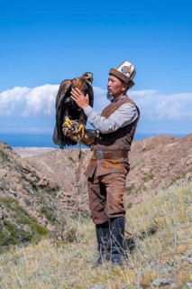 Traditional Kyrgyz eagle hunter with eagle in the mountains, near Kysyl-Suu, Kyrgyzstan, Asia