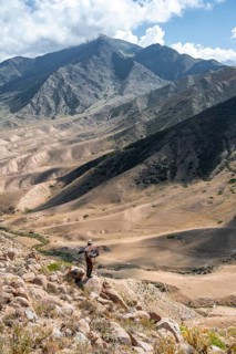 Traditional Kyrgyz eagle hunter hunting in the mountains in a dry landscape, near Kysyl-Suu, Issyk