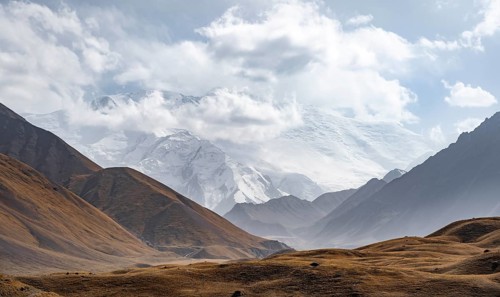 Dramatic mountain landscape, mountain valley, behind glaciated and snow-covered mountain peak Pik