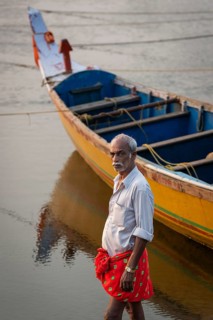Fisherman with red dhoti in front of yellow-blue painted fishing boat, Fort Cochin, Kochi, Kerala,