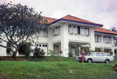 Woman in front of large colonial mansion building originally used by British army, standing by Ford
