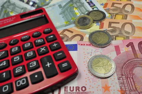Euro banknotes and coins and pocket calculator