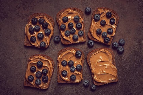 Rye bread with peanut paste and fresh blueberries, top view, no people