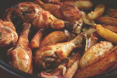 Fried chicken drumsticks with potato slices, in a clay pan, baked in the oven, with spices,